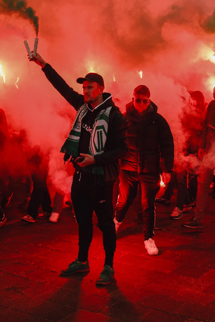 Supporter steekt twee rookfakkels boven de menigte uit