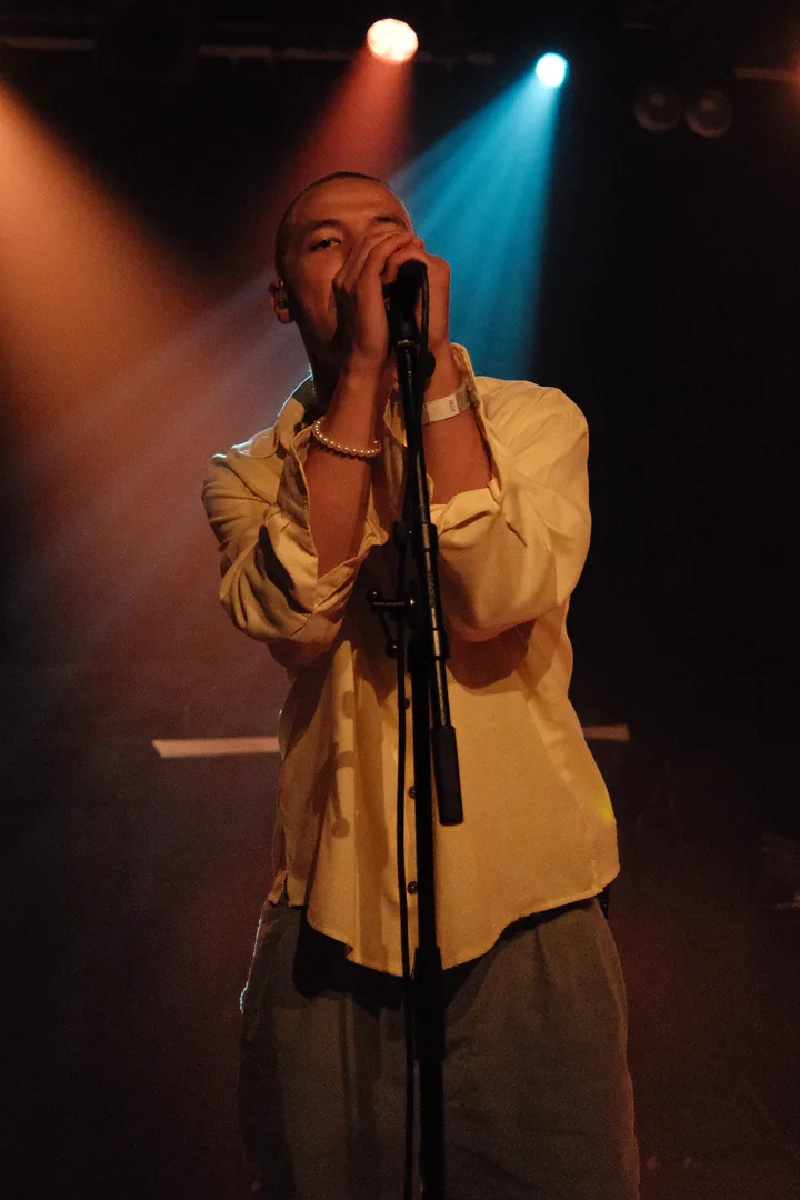 Artiest zingt onder rood en blauw podiumlicht in Simplon Groningen
