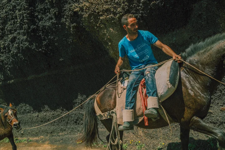 Ruiter op een donker paard in een vulkanisch landschap